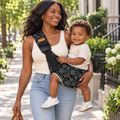 Black mother carrying toddler in the Black Paisley baby sling outdoors