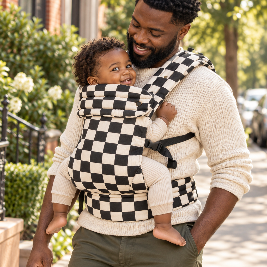 Father carrying toddler in the Née Checkerboard baby carrier outdoors