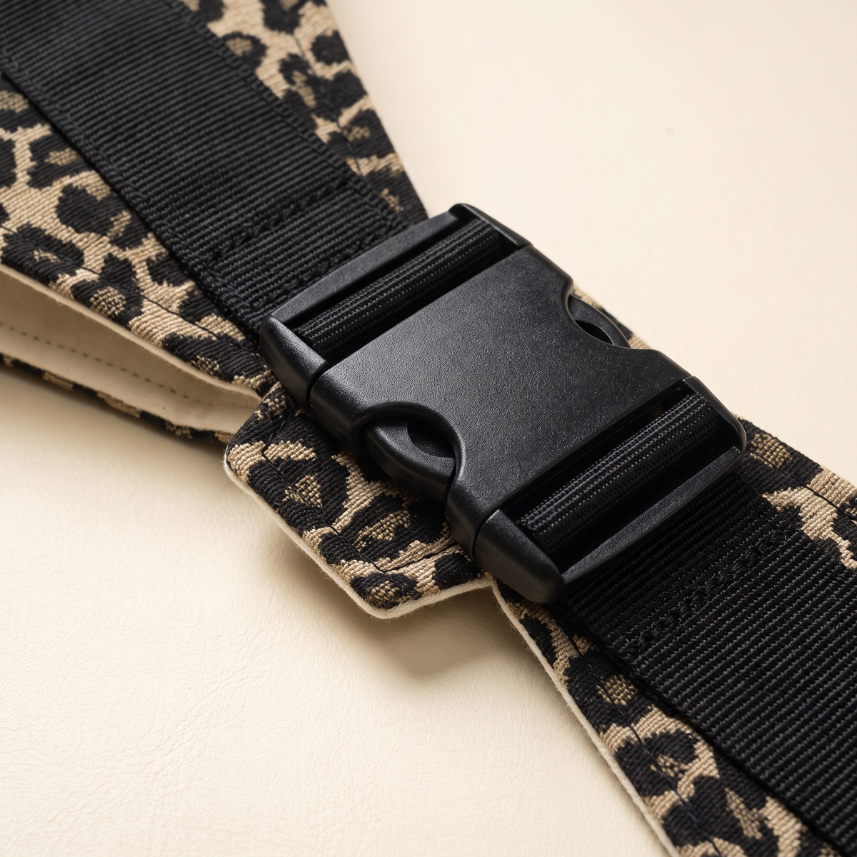 Close-up of black buckle and woven golden leopard sling fabric