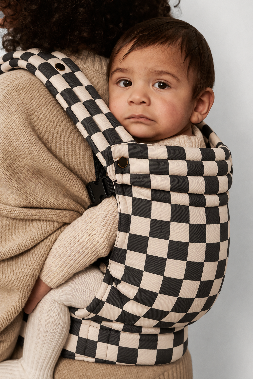 Close-up of baby in the Née Checkerboard ergonomic baby carrier, showing the patterned fabric