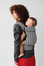 Close view of mother and baby in a back carry in the Née Grand Houndstooth ergonomic baby carrier