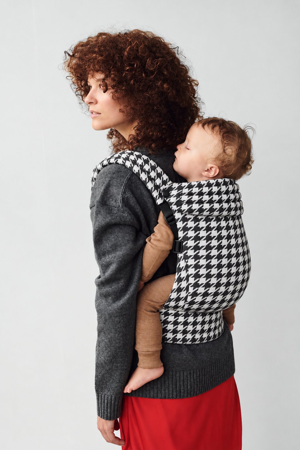 Close view of mother and baby in a back carry in the Née Grand Houndstooth ergonomic baby carrier