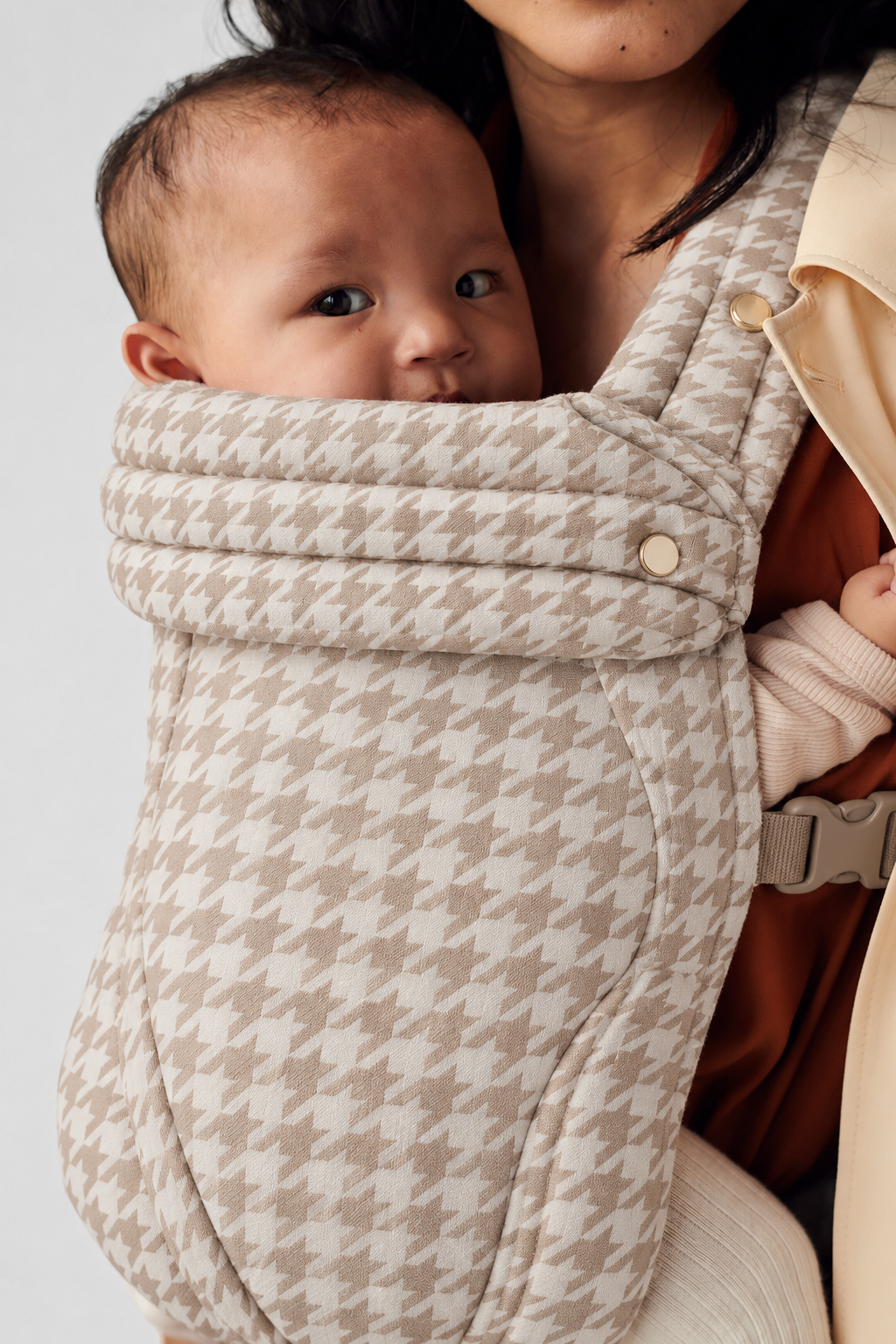 Portrait showing baby and woven fabric details of the Née Khaki Houndstooth ergonomic baby carrier