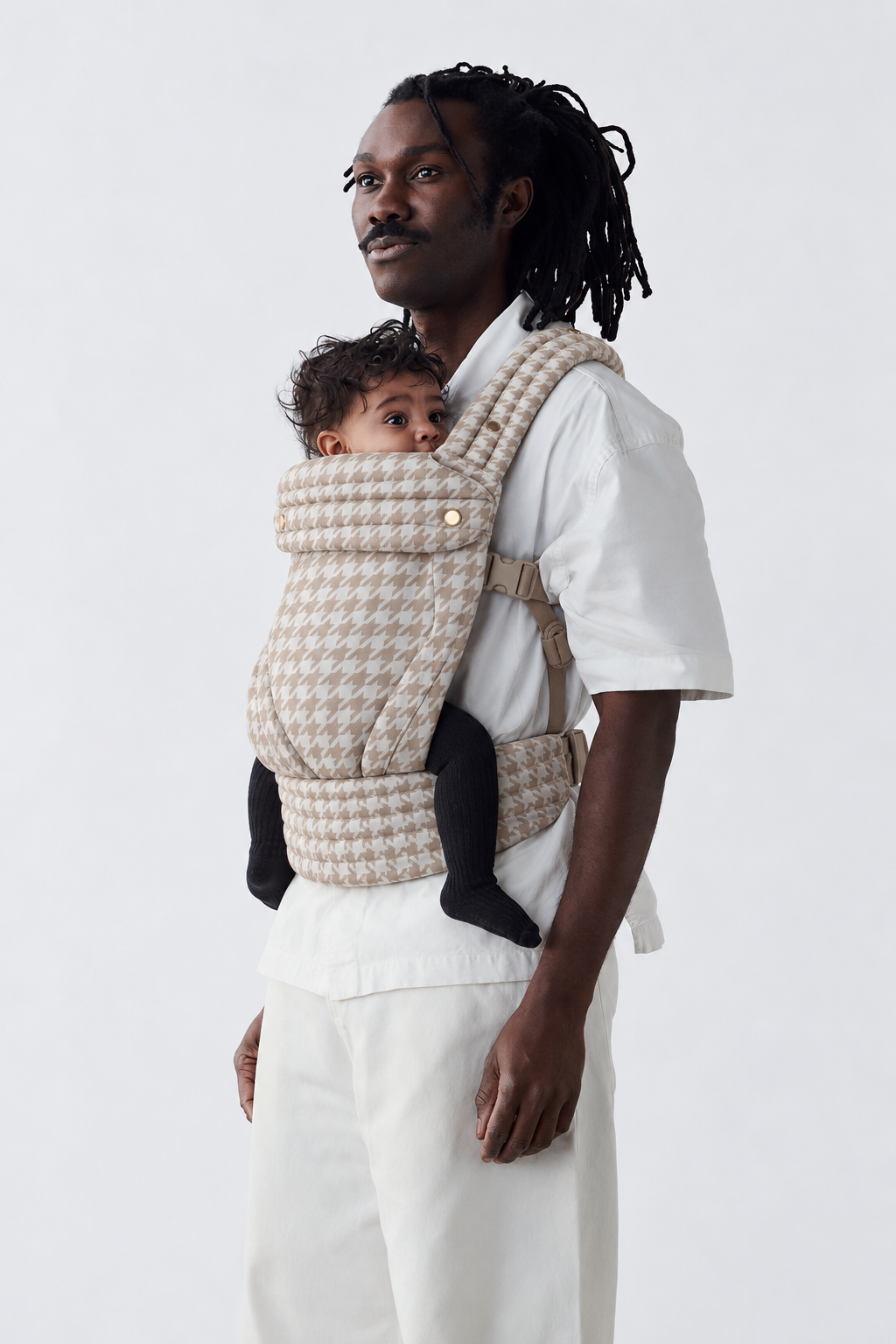 Side view of father wearing the Née Khaki Houndstooth ergonomic baby carrier with baby