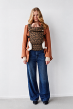 Blonde mother wearing the Née Leopard Print ergonomic baby carrier with baby, full-length view