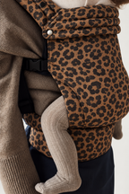 Close-up of the Née Leopard Print ergonomic baby carrier fabric, waistband and baby