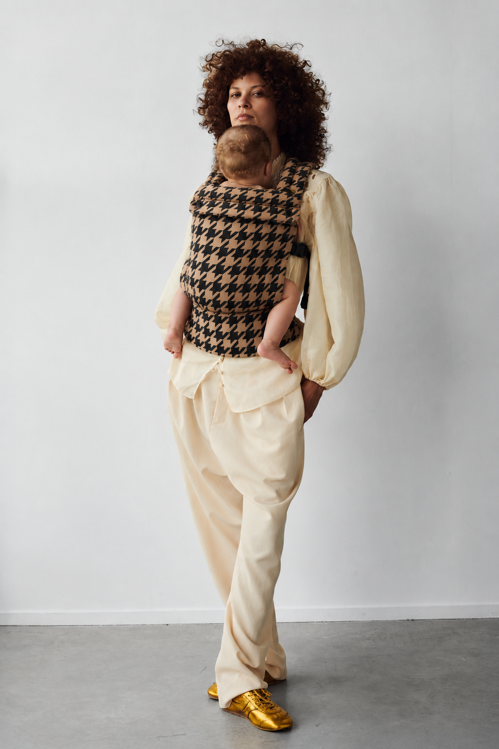 Mother wearing the Née Noir Houndstooth ergonomic baby carrier with baby, full-length view