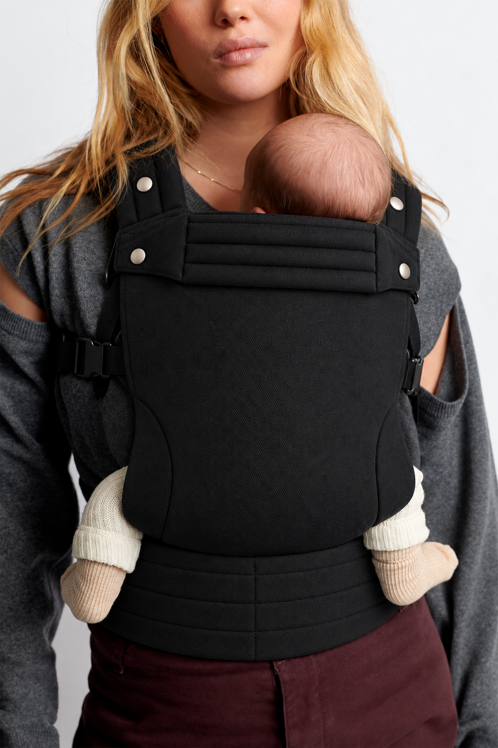 Close-up of a baby in the Née Onyx Black ergonomic baby carrier, showing the textured fabric panel and waistband
