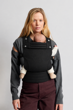 Close view of a mother wearing the Née Onyx Black ergonomic baby carrier with her baby in a front carry