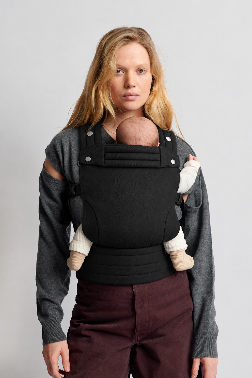 Close view of a mother wearing the Née Onyx Black ergonomic baby carrier with her baby in a front carry