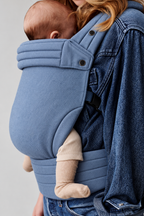 Close-up of baby in the Née Powder Blue ergonomic baby carrier, showing the fabric panel and waistband